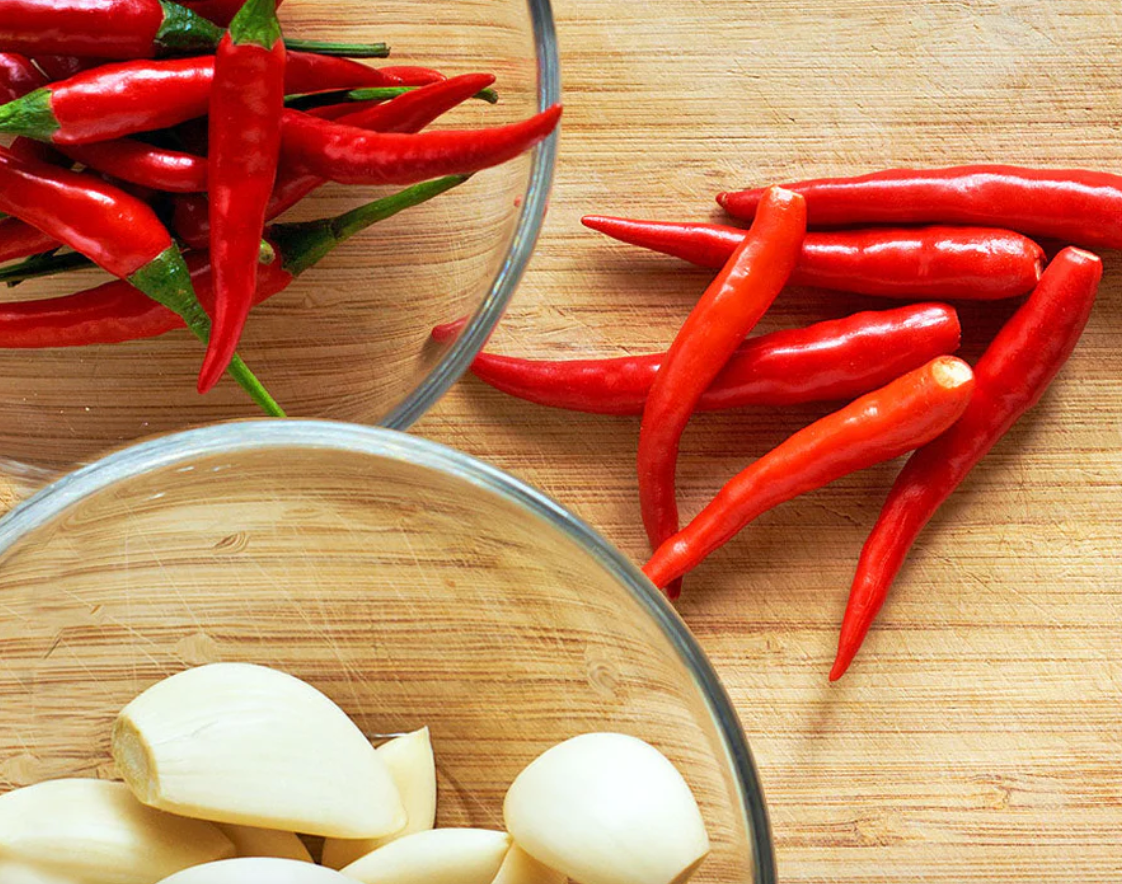 Red chili peppers and garlic cloves on a wooden surface